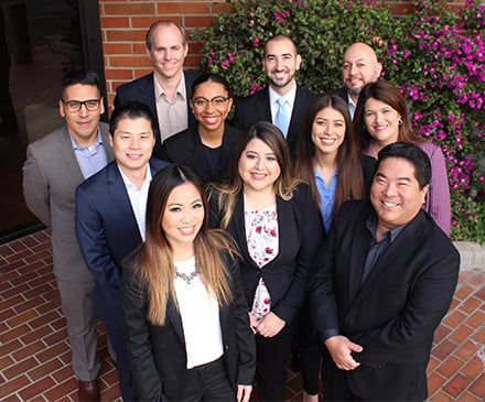 Diverse group of SchoolsFirst FCU employees smiling at the camera.